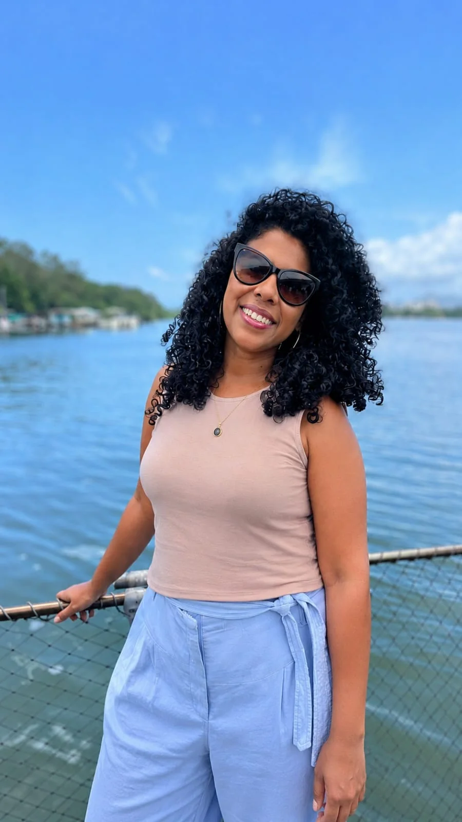 Renata Lima ao ar livre, à beira da água, em um dia de sol